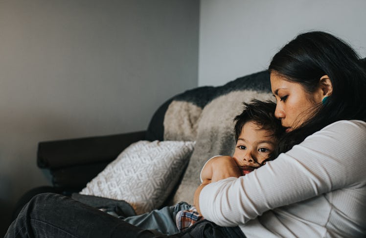 An anxious boy is hugged by his mother on the couch.