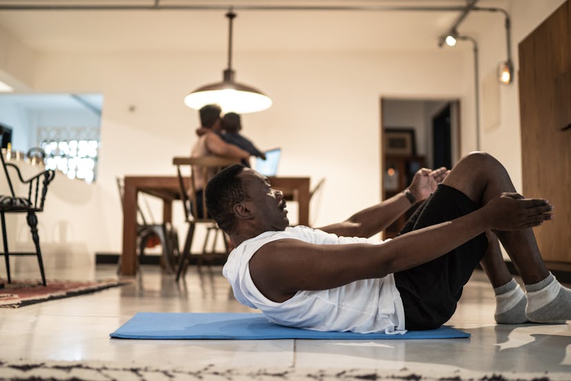 A man at home doing a reverse crunch on a yoga mat.