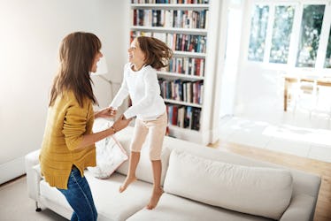 A child with ADHD jumps on the couch while laughing with mom.