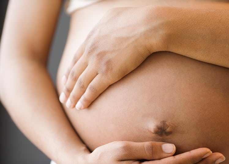 Close up of a pregnant person's baby bump.