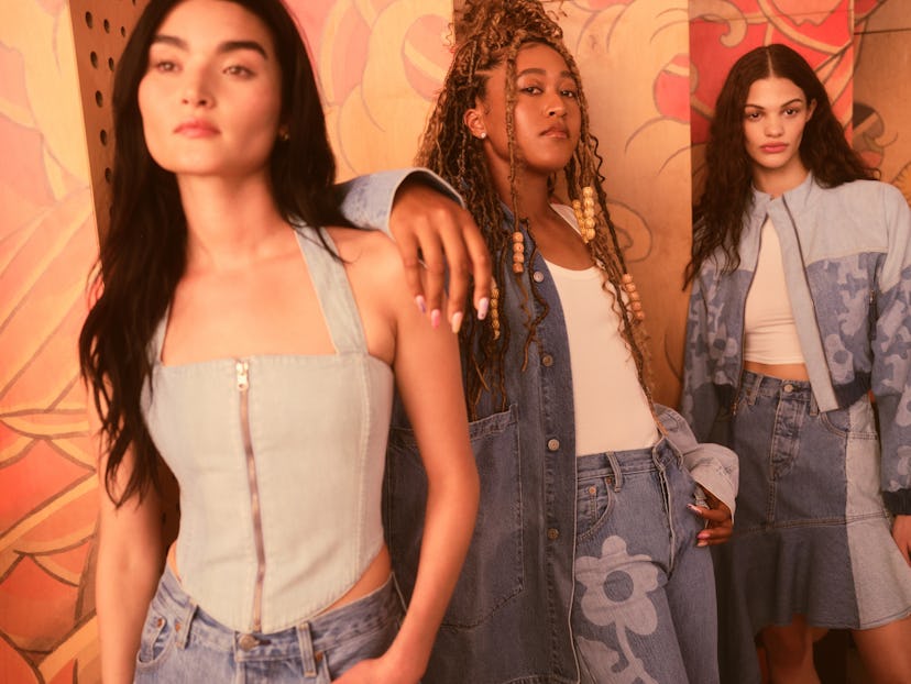 Naomi Osaka in a patchwork-style blue denim jacket and blue denim jeans next to two models in simila...