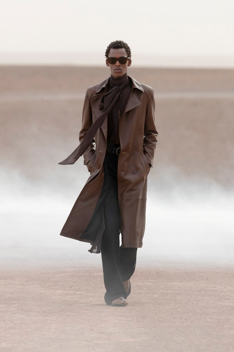 A model wearing a brown Saint Lauren coat and scarf at the Men’s Fashion Week Spring 2023