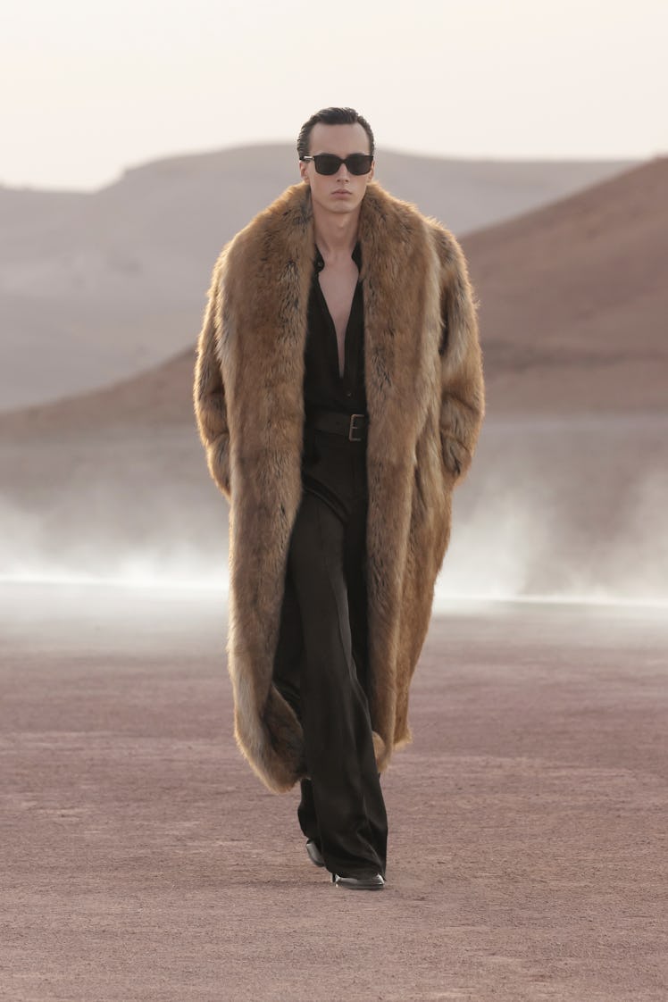 A model wearing a brown fur coat, black trousers and top by Saint Laurent at the Men’s Fashion Week ...