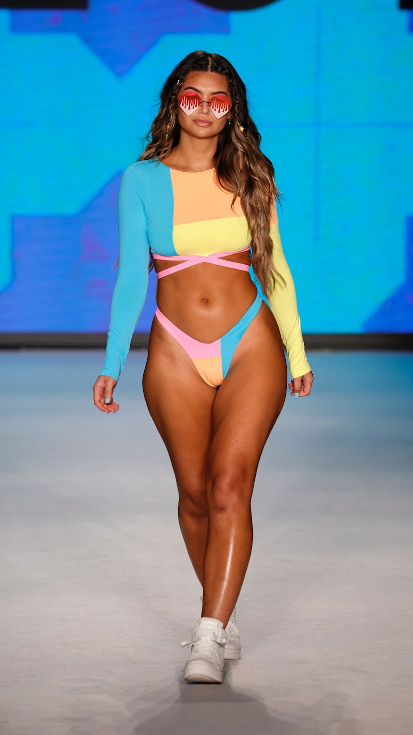 A young model walking in a blue, pink, orange, and yellow swimsuit at Paraiso Miami Beach Swim Week