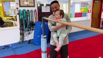 Jett grabs the bars as Coach Chow holds him up.