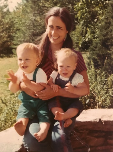 The artist Katherine Bradford holding her two young children, sitting outside in the sun in the 1970...