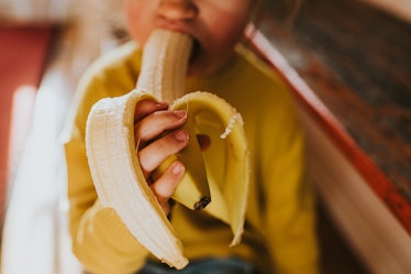A young girl eating a banana.