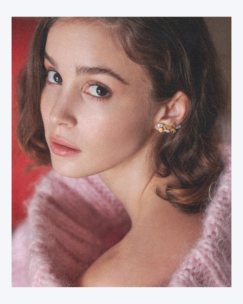 Alba Baptista wearing a pink sweater and looking over her shoulder