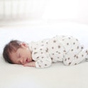 A baby sleeps in a onesie covering in stars. 