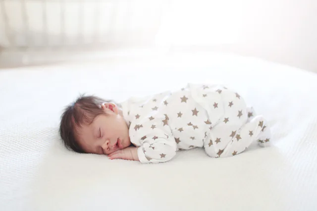 A baby sleeps in a onesie covering in stars.