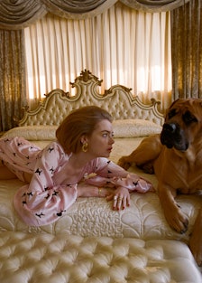 Emma Stone lying on a big bed with a bigger dog