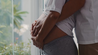 A man holds his pregnant wife's belly.