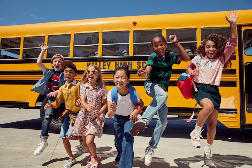 happy kids jumping next to a school bus,  first day of school instagram captions