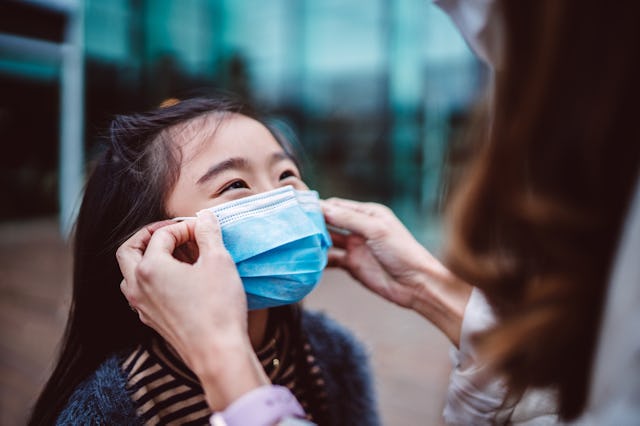 Is double-masking effective? A mother helps her daughter adjust her mask, as experts say fit is the ...