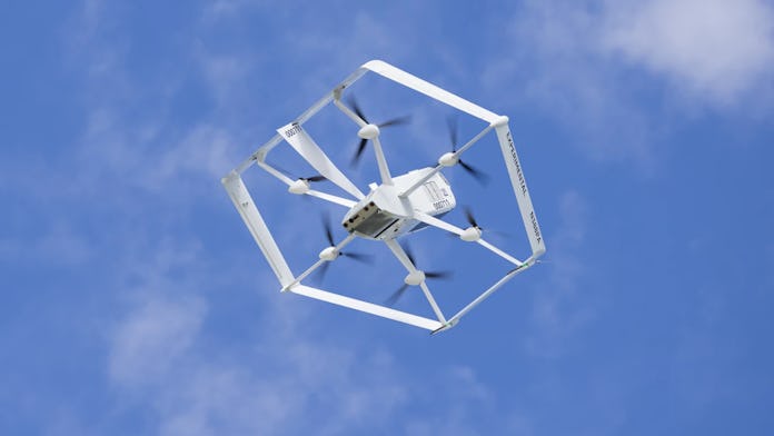 A hexagonal drone flying in front of a blue sky with clouds.