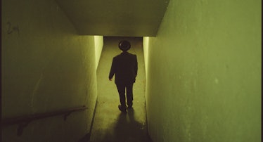 An eery photo of a person standing at the bottom of a stairwell.