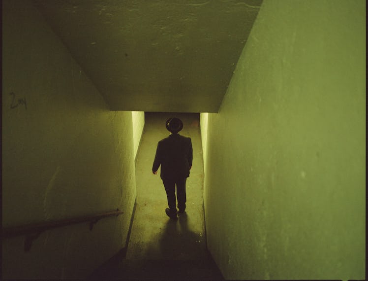 An eery photo of a person standing at the bottom of a stairwell.