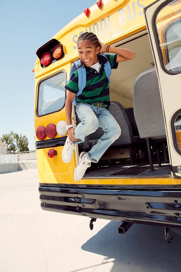 happy child striking pose and jumping from the back of a school bus, first day of school instagram c...