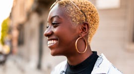 Young woman smiling during the July 2022 new moon in Leo, which will affect every zodiac sign's conf...