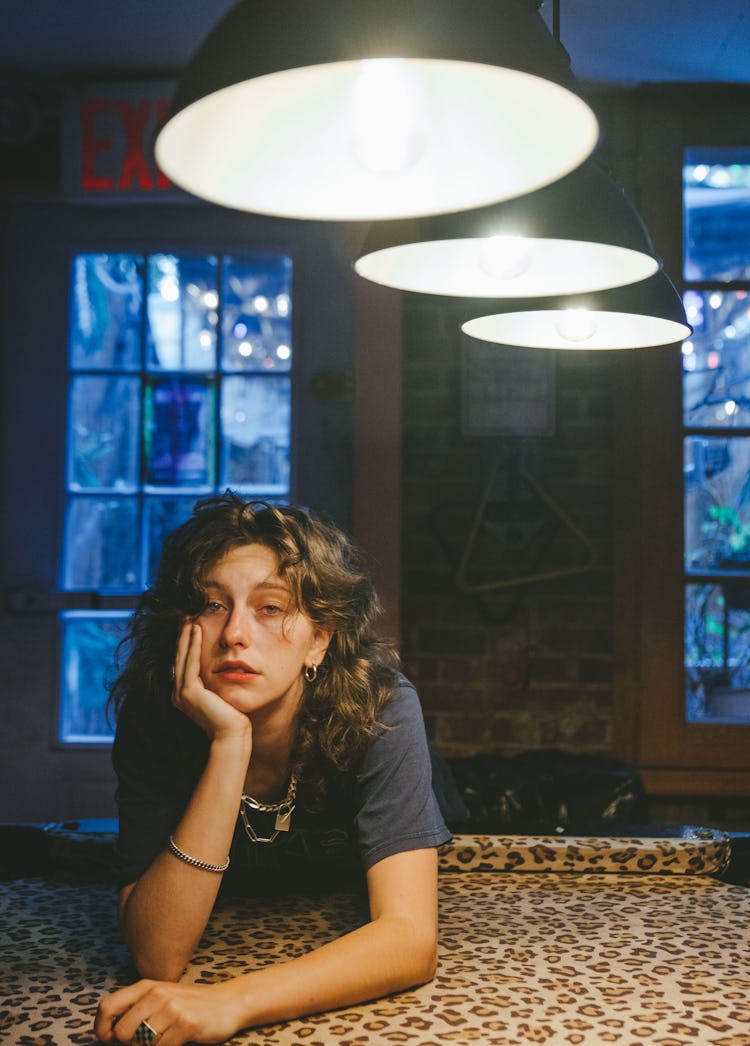 Musician Mikaela Straus known by her name King Princess laying on a leopard blanket under three chan...