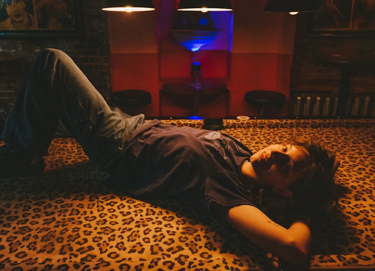 Musician Mikaela Straus known by her name King Princess laying on a blanket with a leopard print