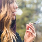 A pregnant woman smoking marijuana outdoors.