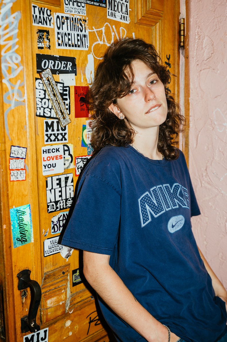 Musician Mikaela Straus known by her name King Princess leaning on a wall while biting her lip