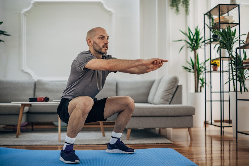 A man does a squat jump at home.