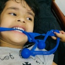 A preschooler biting a stretchy blue toy.