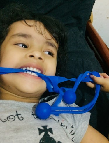 A preschooler biting a stretchy blue toy.