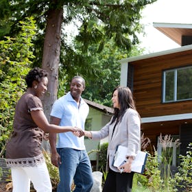 Couple shaking hands with retailer outside of newly bought home