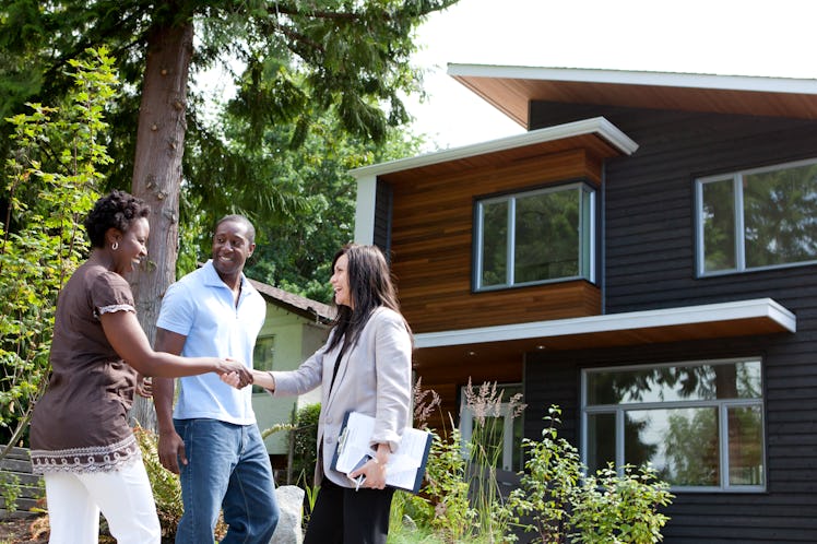 Couple shaking hands with retailer outside of newly bought home