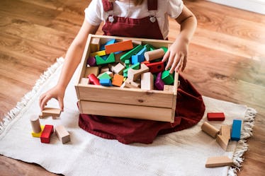 A child puts toy blocks away into a box.