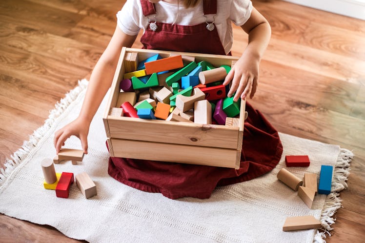 A child puts toy blocks away into a box.