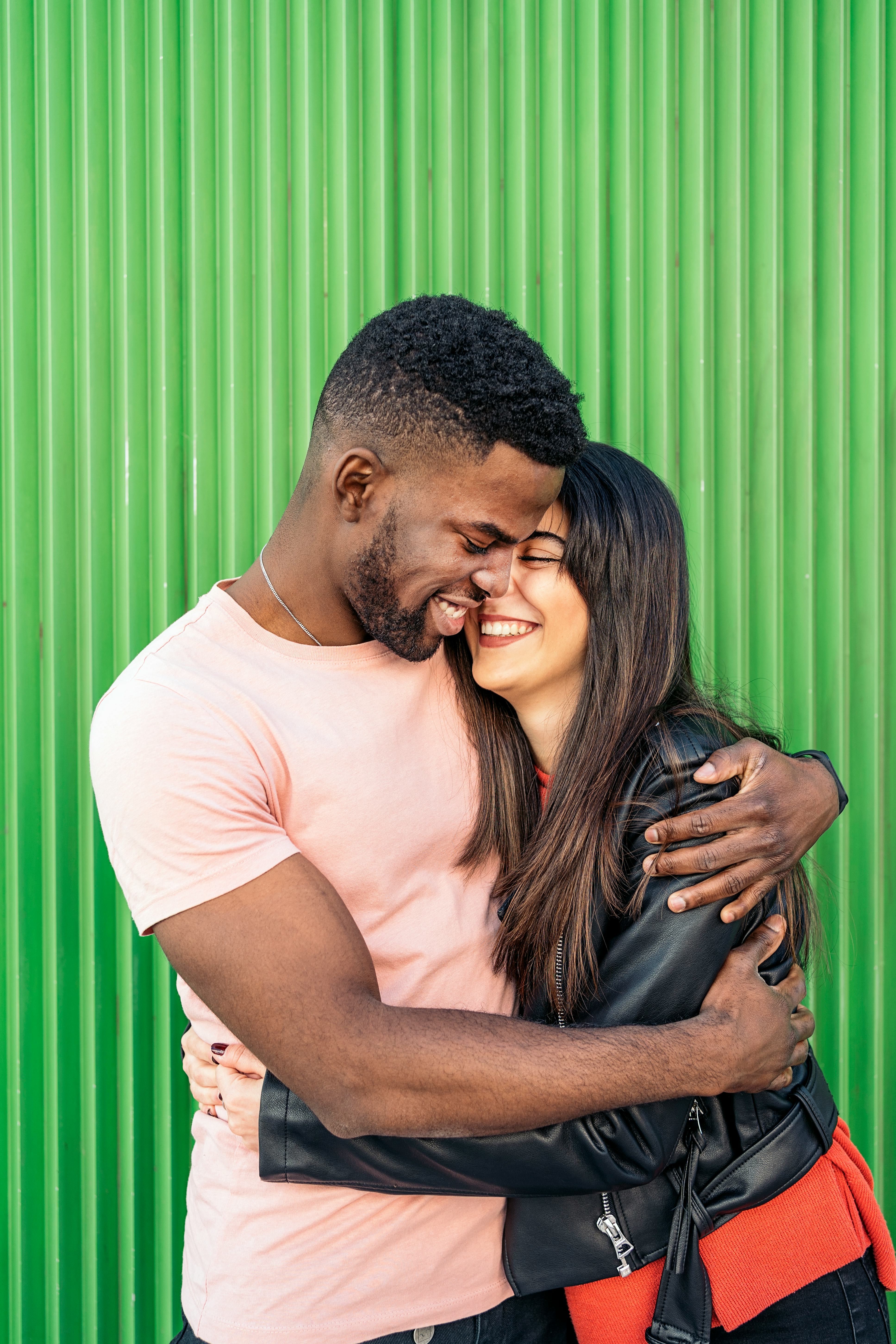 Young couple laughing in front of green background on the most romantic day in August 2022 for every...