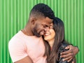 Young couple laughing in front of green background on the most romantic day in August 2022 for every...