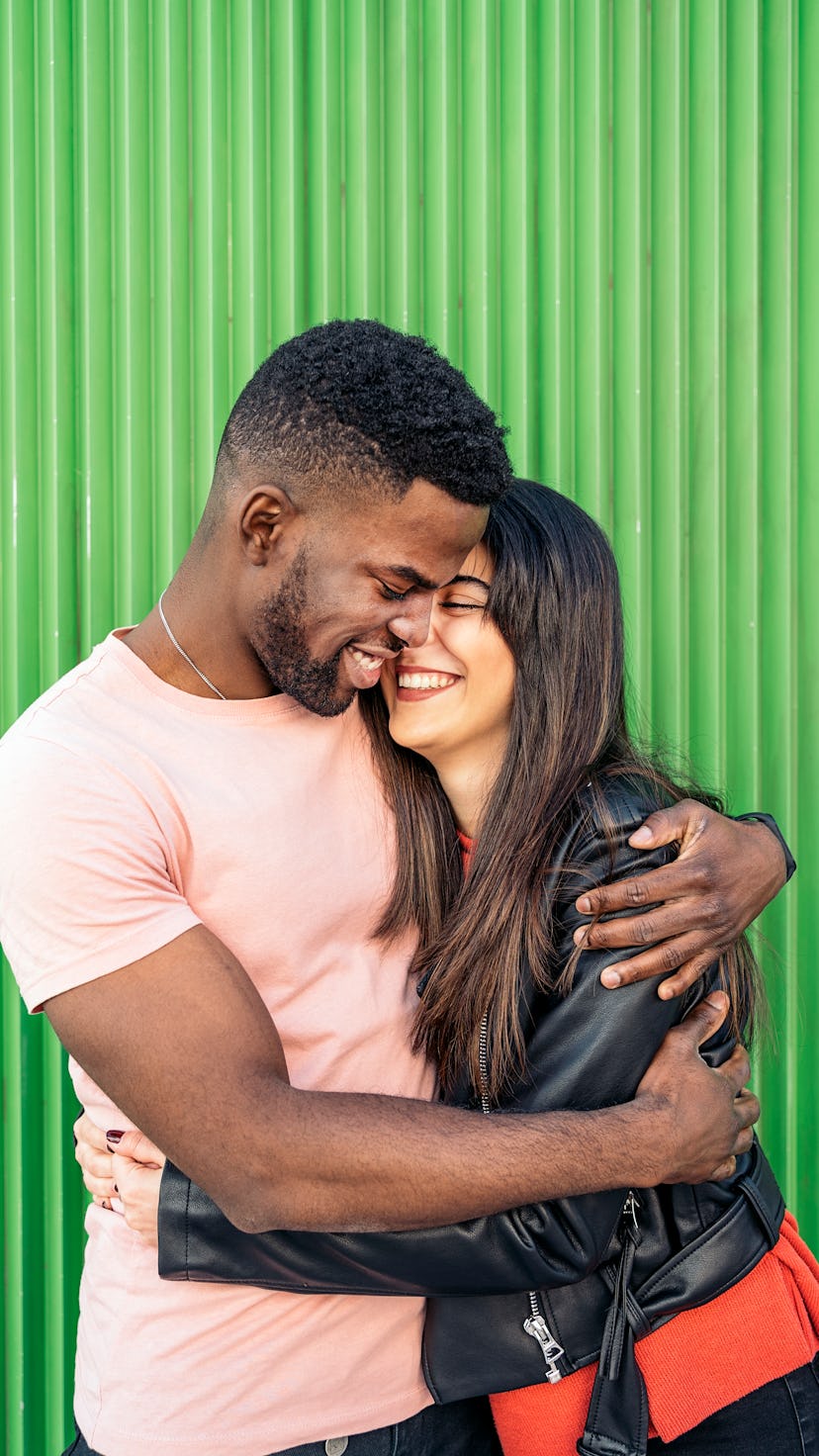 Young couple laughing in front of green background on the most romantic day in August 2022 for every...