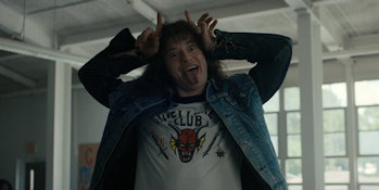 long haired man in a jean jacket making a silly face with his hands 