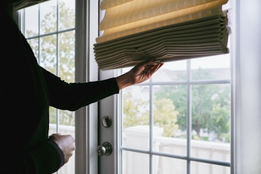 Person closing blind on door window