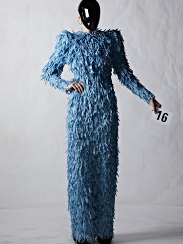 A model in a blue Balenciaga feather dress with a black plexiglass face shield