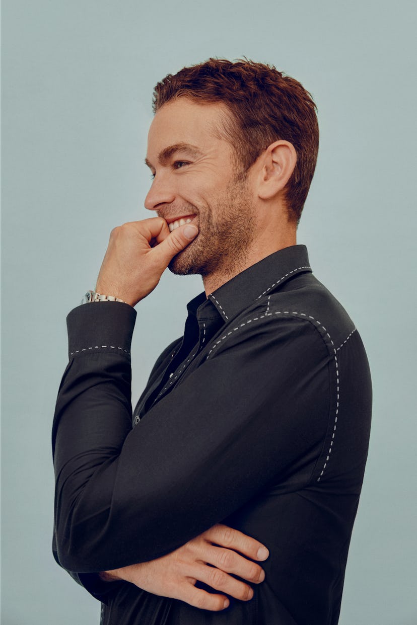 Chace Crawford smiling in a Paul Smith black shirt and beige pants and a Rolex watch