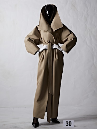 A model in a floor length Balenciaga coat with a black plexiglass face shield