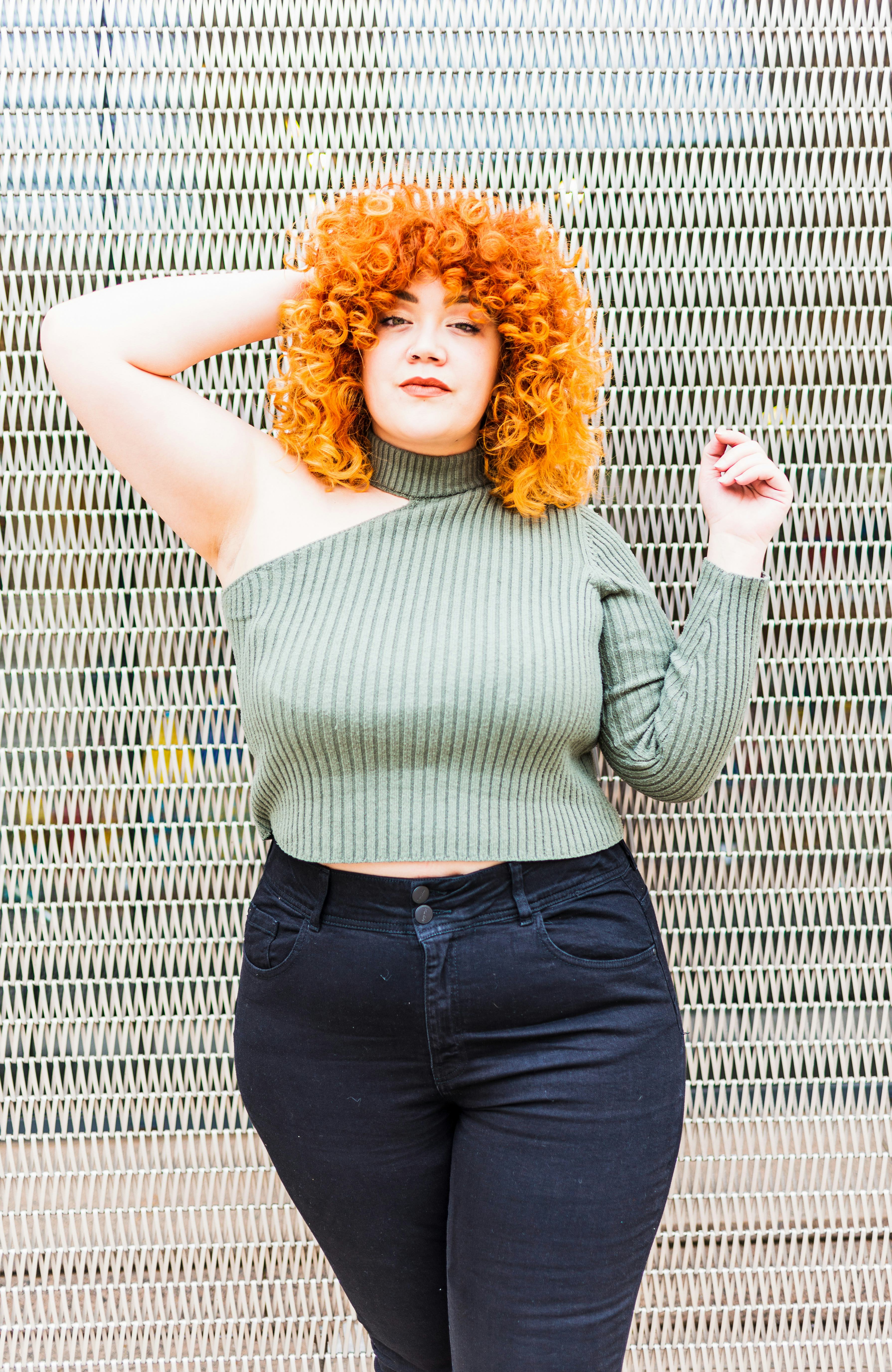 Young woman with curly red hair, waiting to hear her signature scent for summer 2022.