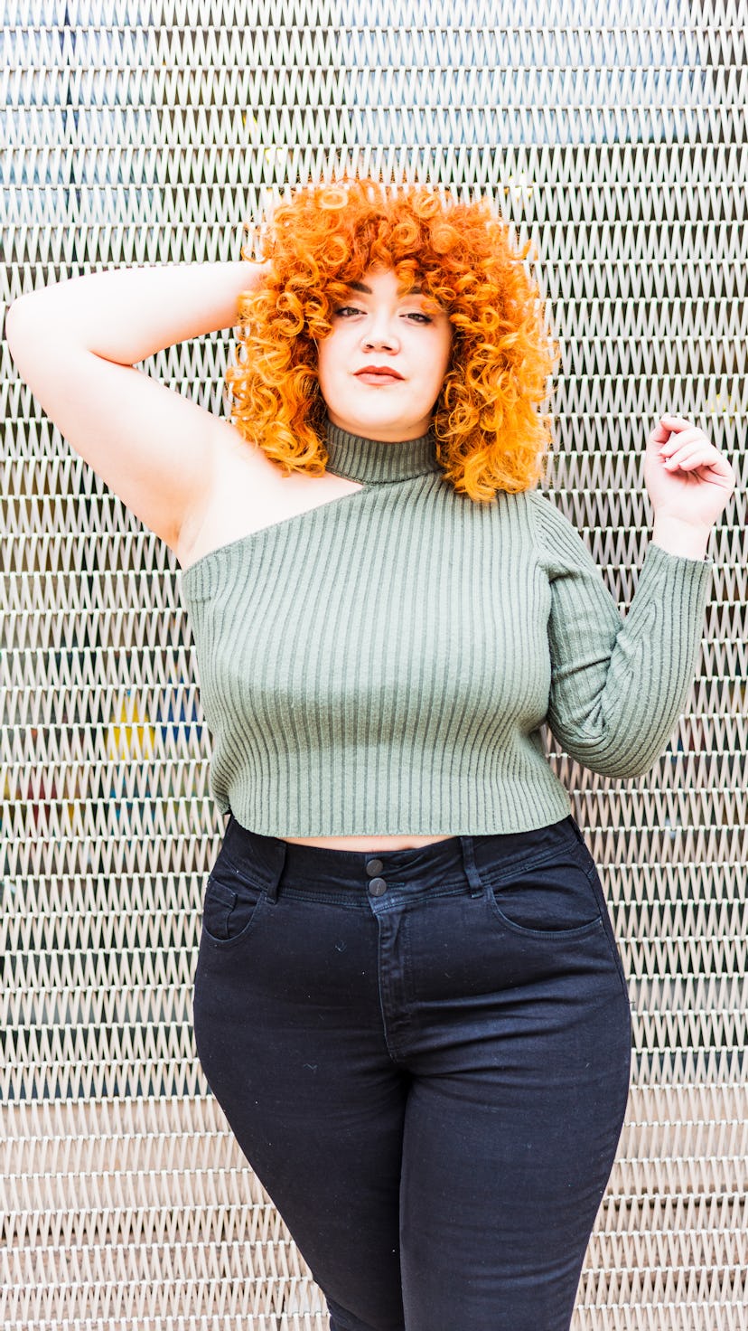 Young woman with curly red hair, waiting to hear her signature scent for summer 2022.