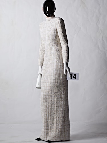 A model in a off white Balenciaga dress with a black plexiglass face shield