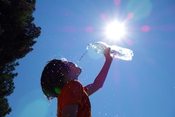 Boy drinking water outdoors as the sun shines overhead