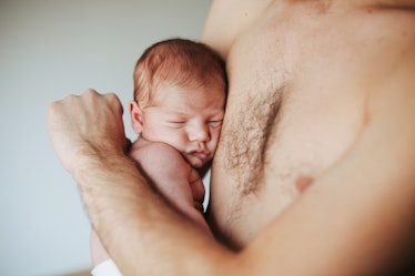 A dad holding his baby against his bare chest.