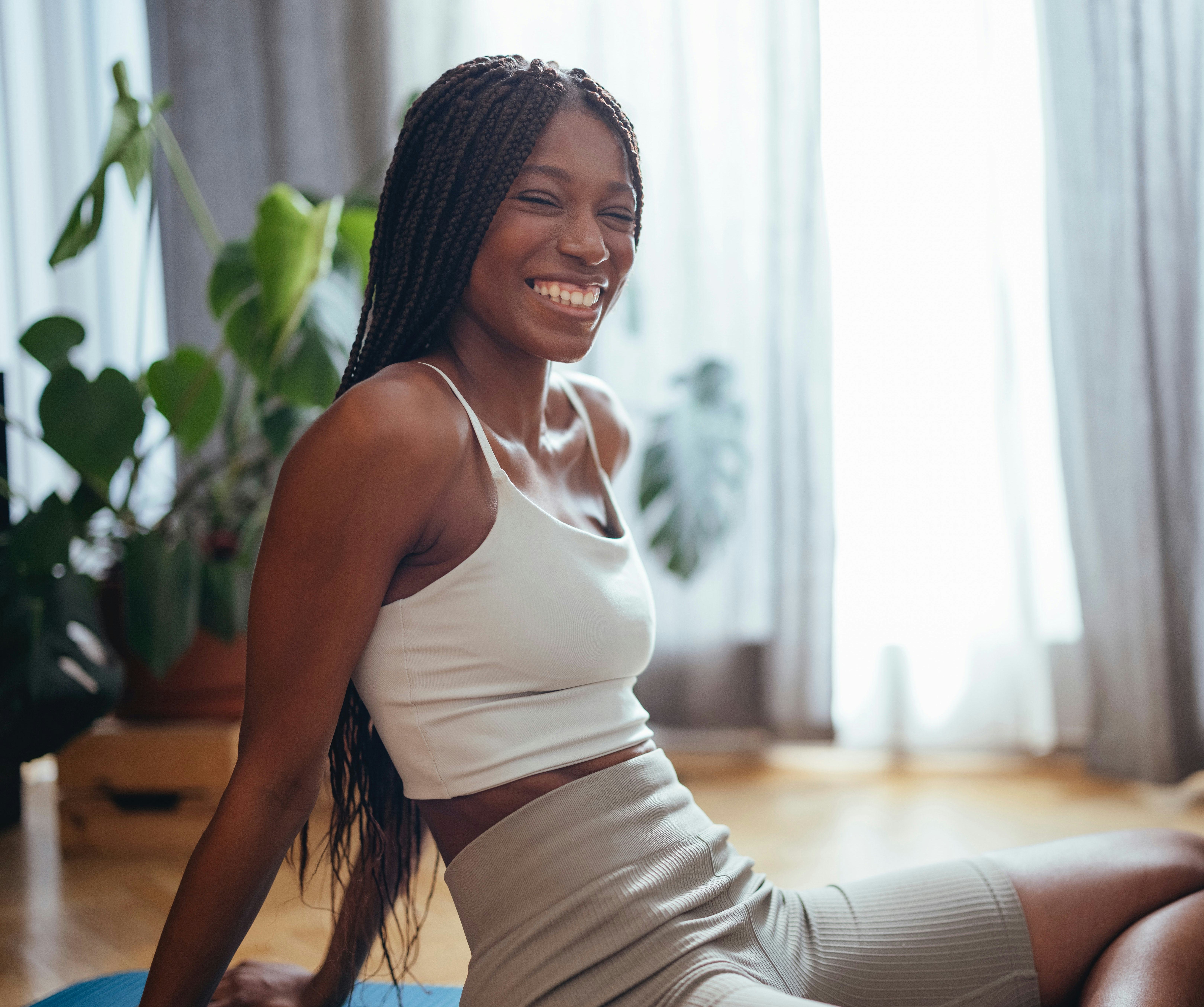 A woman performs a quick pilates workout for summer 2022 at home, according to a celebrity pilates t...