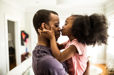 A daughter kisses her dad on the nose.