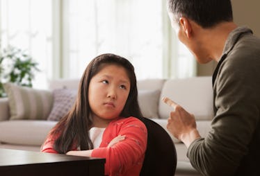 A child being disciplined by her father crosses her arms.